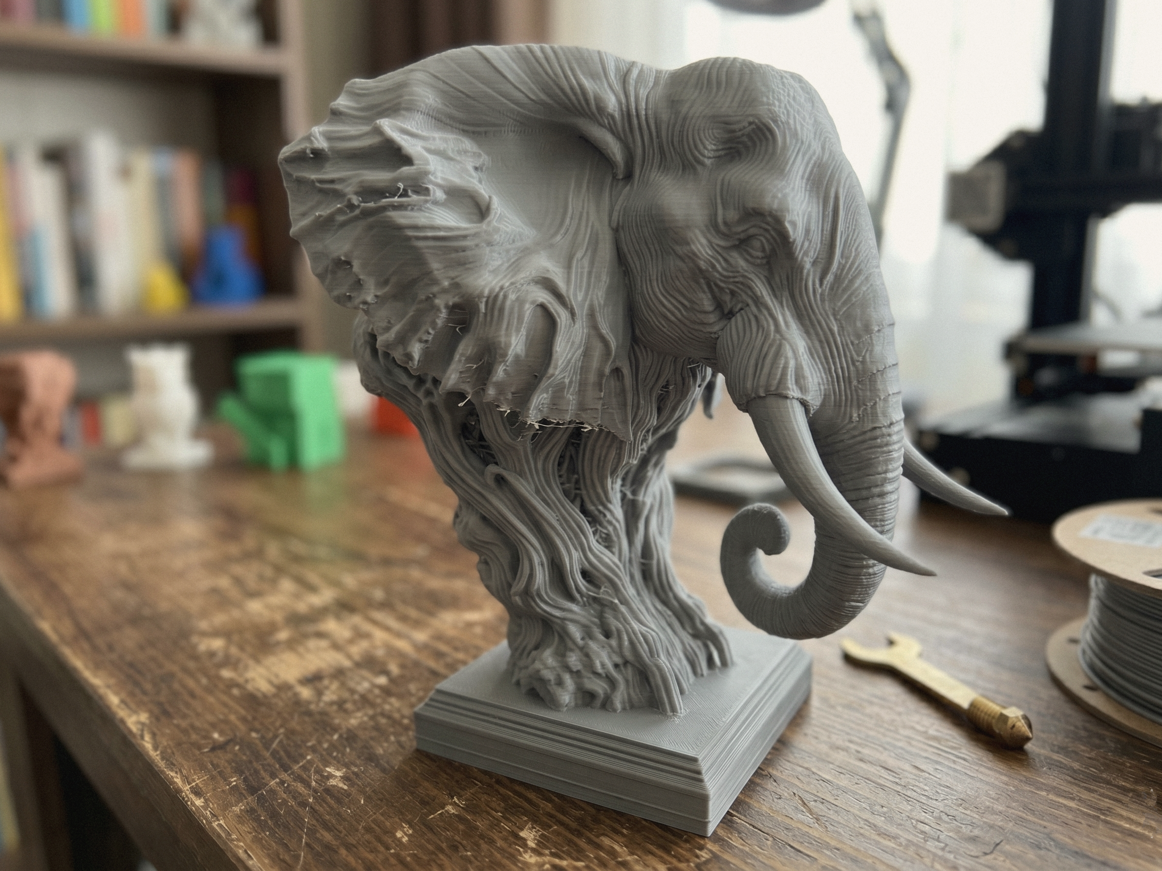 Buste d’éléphant sculpté gris, vue inclinée avec trompe et oreille visibles.
